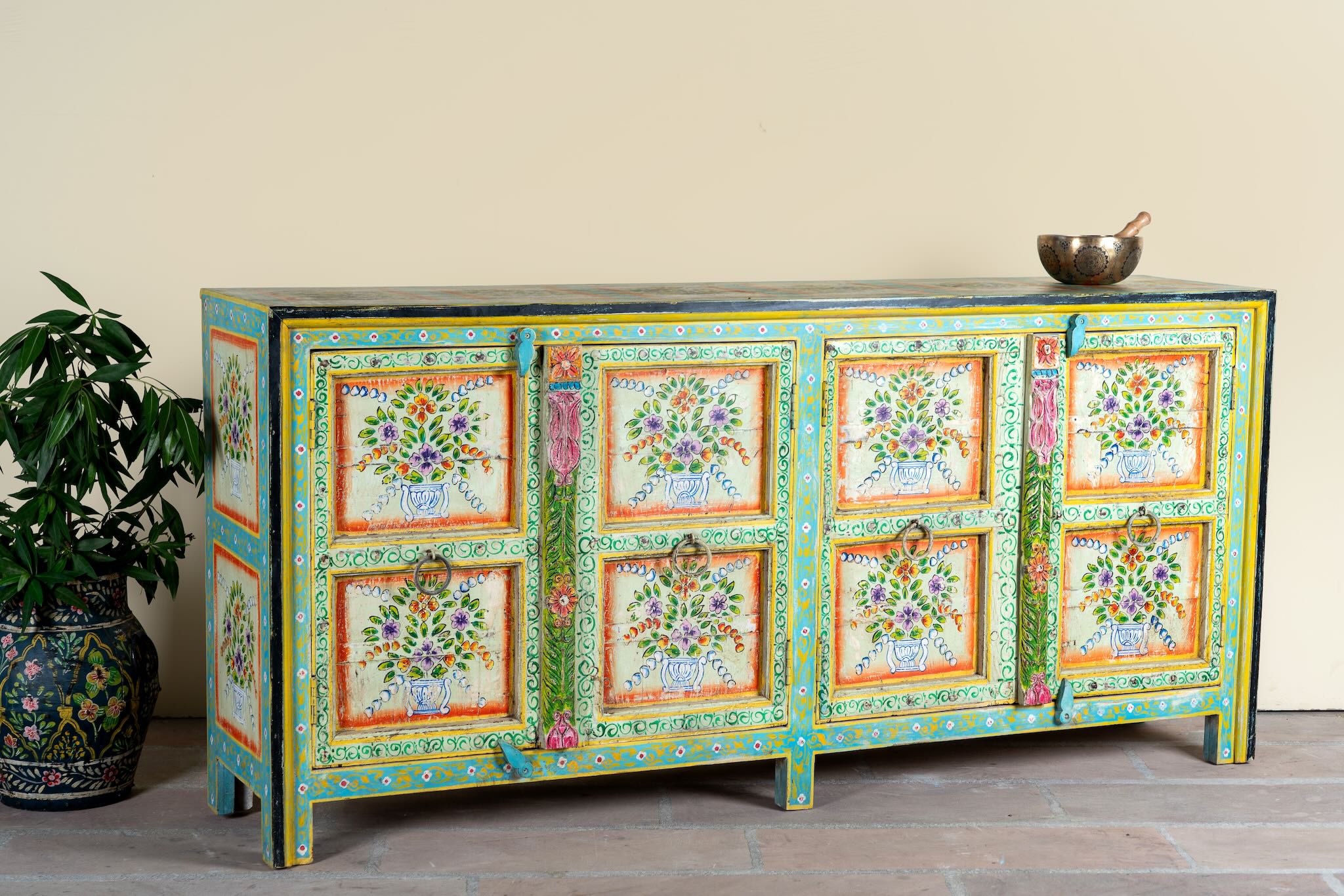 Side angle image of a vintage green sideboard reclaimed wood with hand painted floral motifs and distressed finish; artisanal storage furniture for bohemian interiors, 170 × 40 × 104 cm.