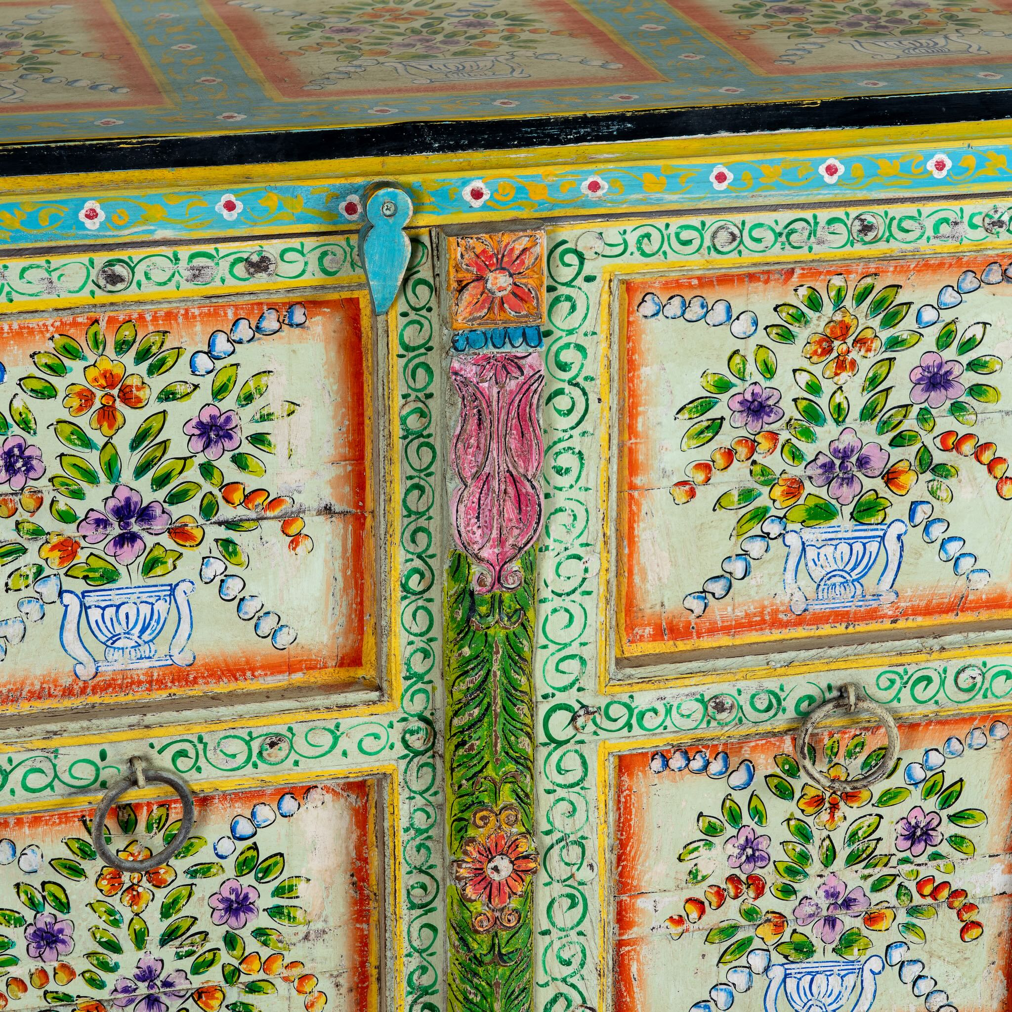 Close up image of a reclaimed wood sideboard with hand painted floral motifs and distressed finish; artisanal storage furniture for bohemian interiors, 170 × 40 × 104 cm.