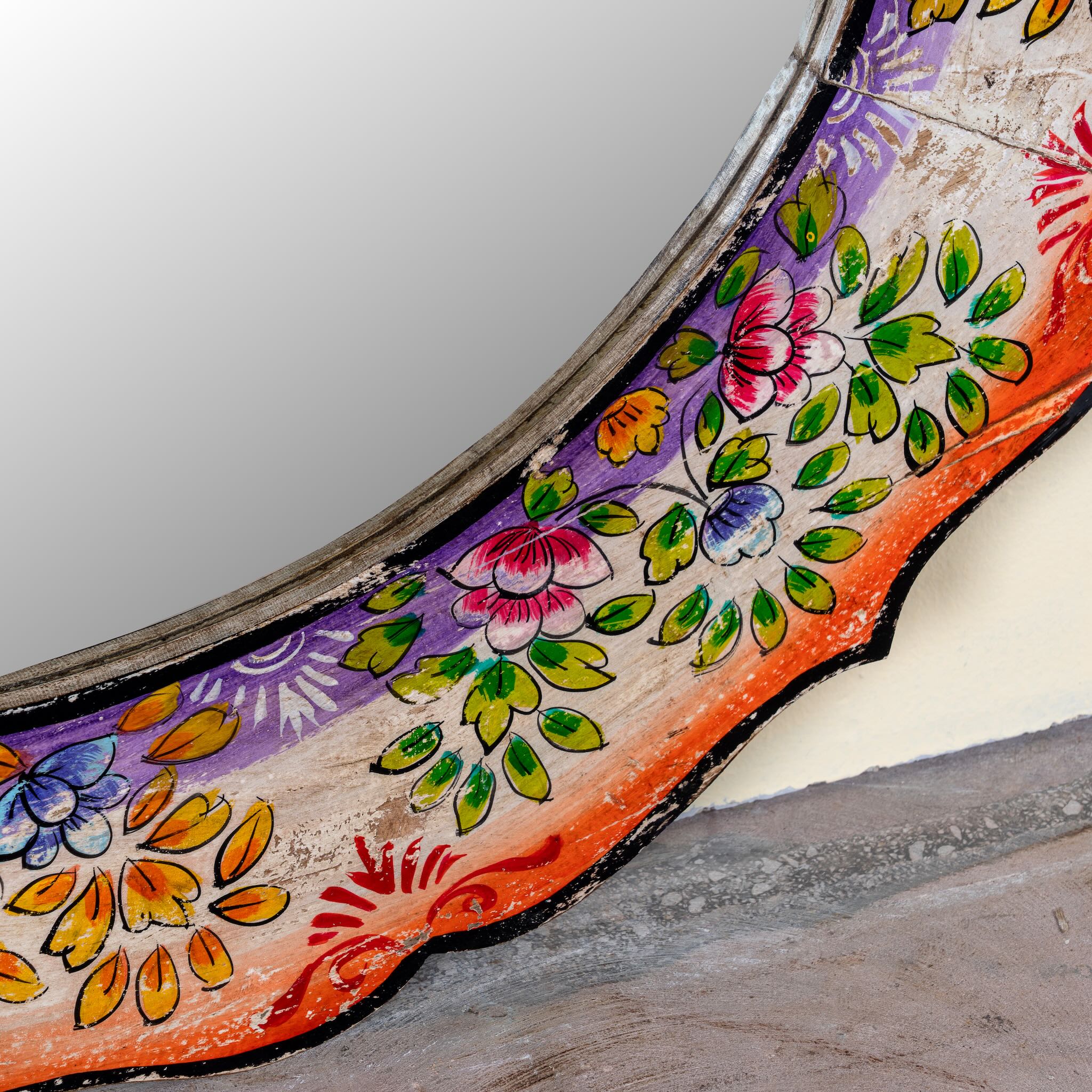 Close up image of a Yagna hand-painted round reclaimed wood mirror with colourful floral artwork, scalloped vintage frame, and artisan detailing, 90cm diameter.