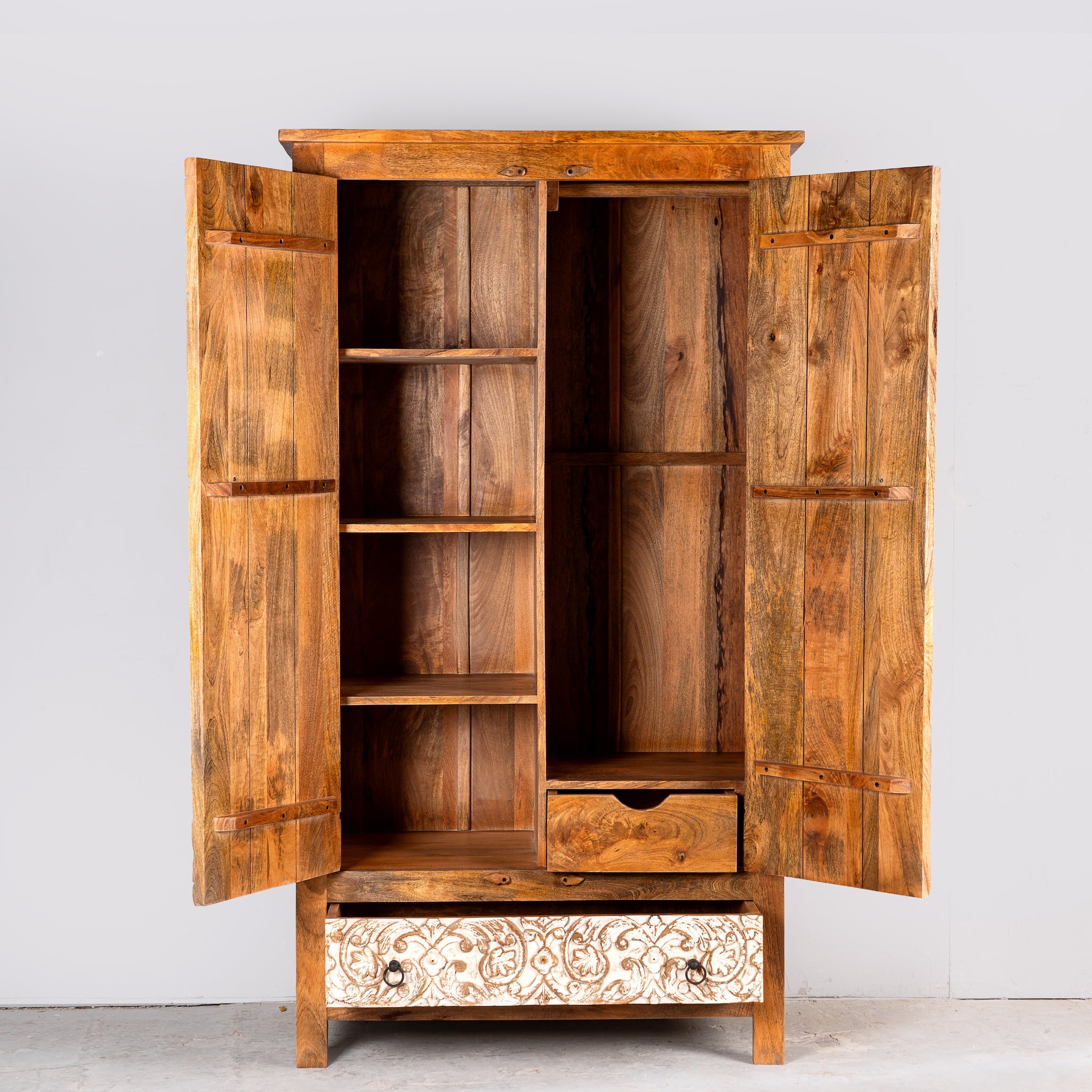 Image showing inner layout with drawers and shelfs of a hand-carved mango wood wardrobe with whitewashed floral motifs – Zashil by Om Home & Garden, a Mediterranean-inspired piece of carved wooden furniture.