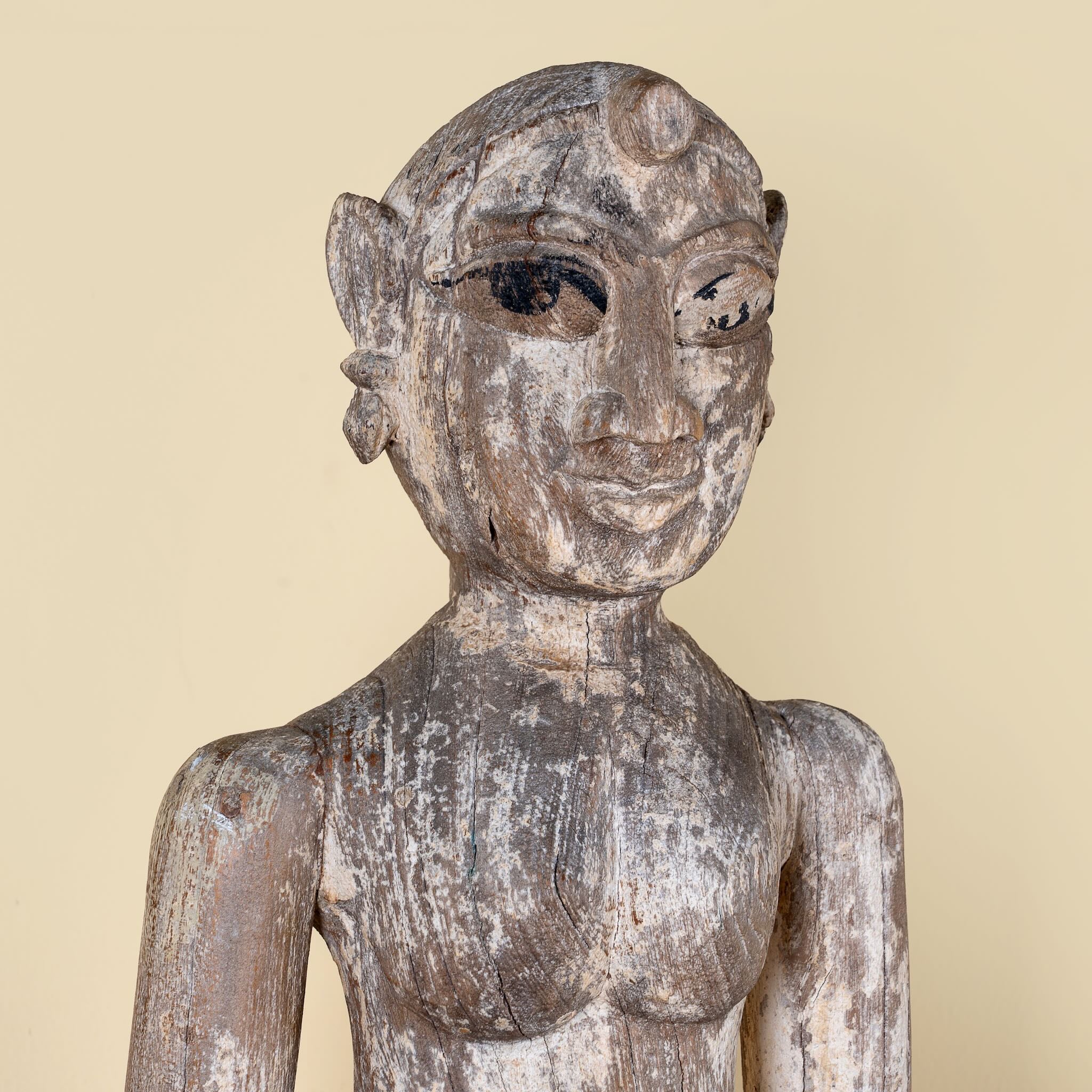 Close up image of an antique Indian wooden temple guardian figure.