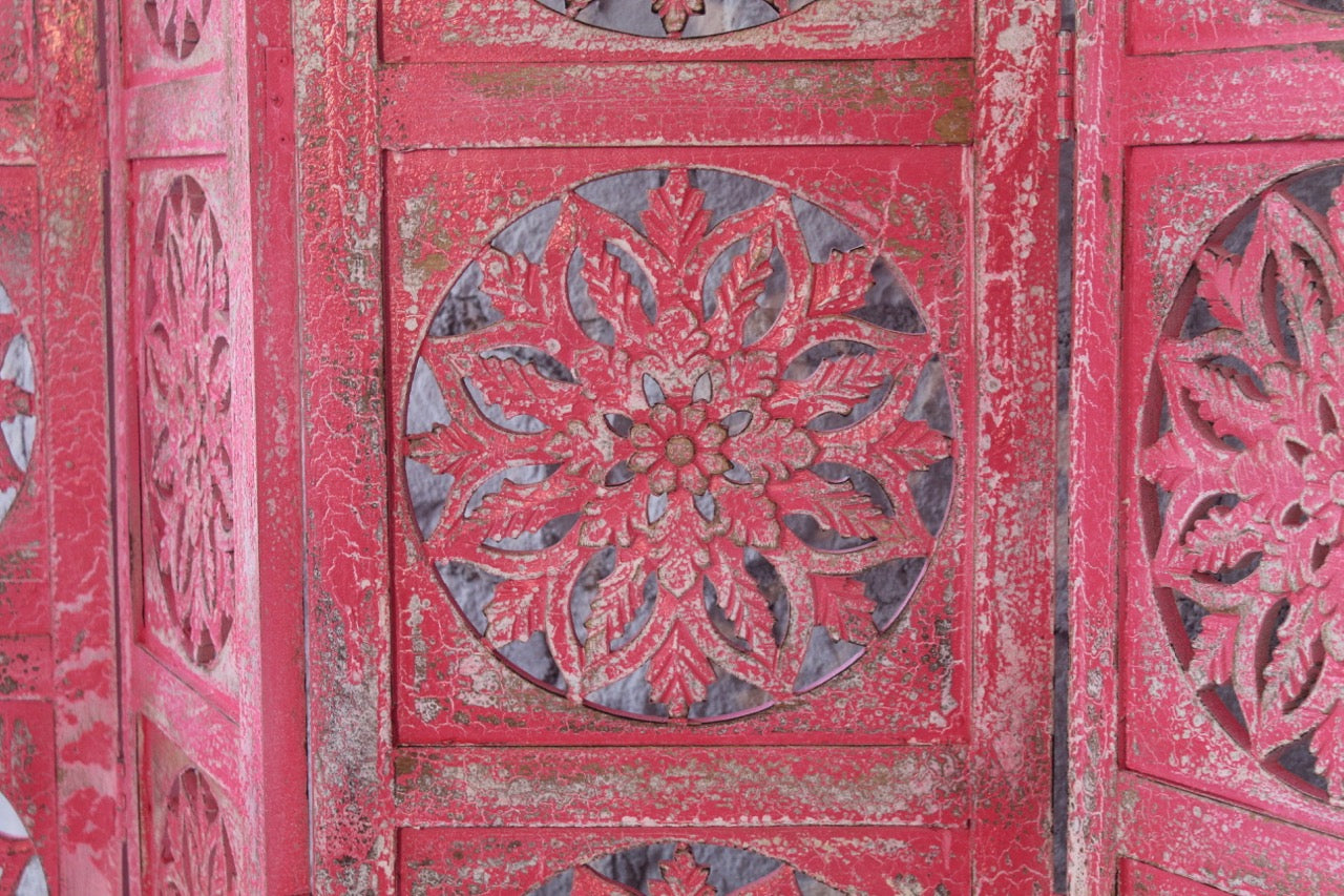 Close up image of a hand-carved pink mango wood folding room divider with delicate carved patterns, natural variations, and warm boho style for unique interiors.