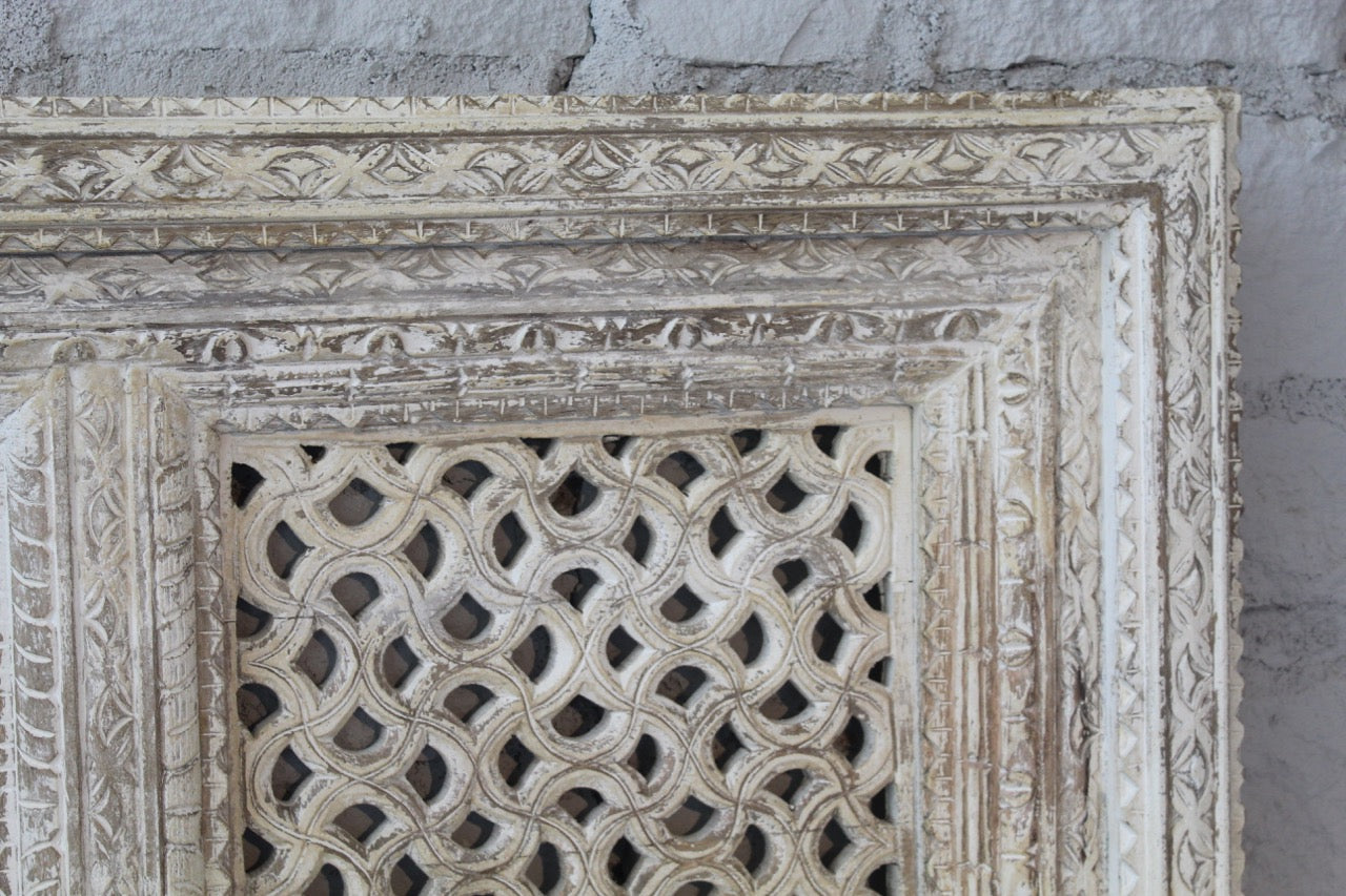 Close up image of a square mango wood wall panel Akupara with intricate hand-carved detailing in soft, natural tones. A piece of unique wooden wall art perfect for wood wall decoration and carved wood furniture collections.