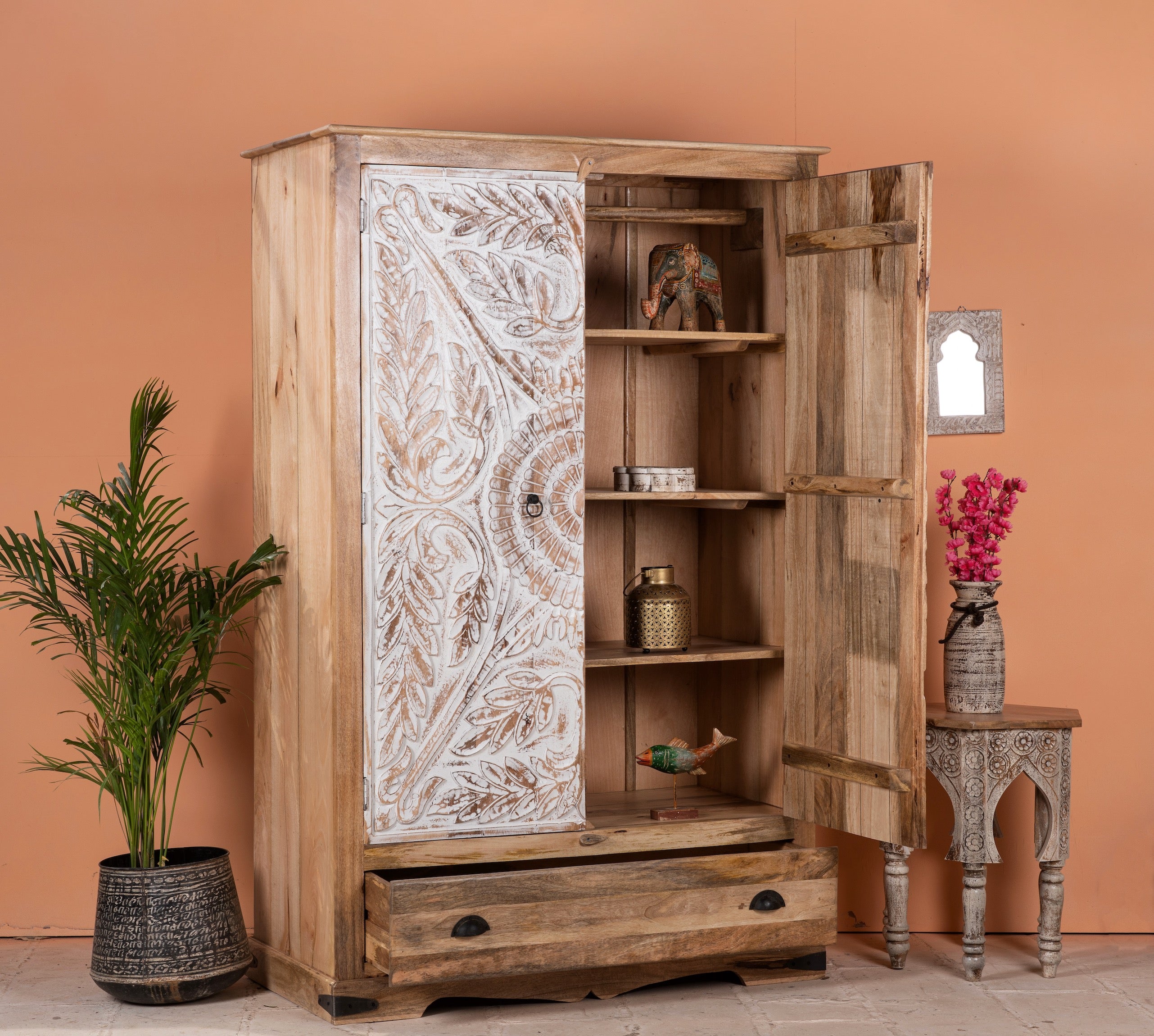 Side angle image with open door of a Cheyyur handcrafted solid mango wood wardrobe with hand-carved whitewashed doors, large storage drawer, traditional Indian detailing, and natural wood grain, 190cm.