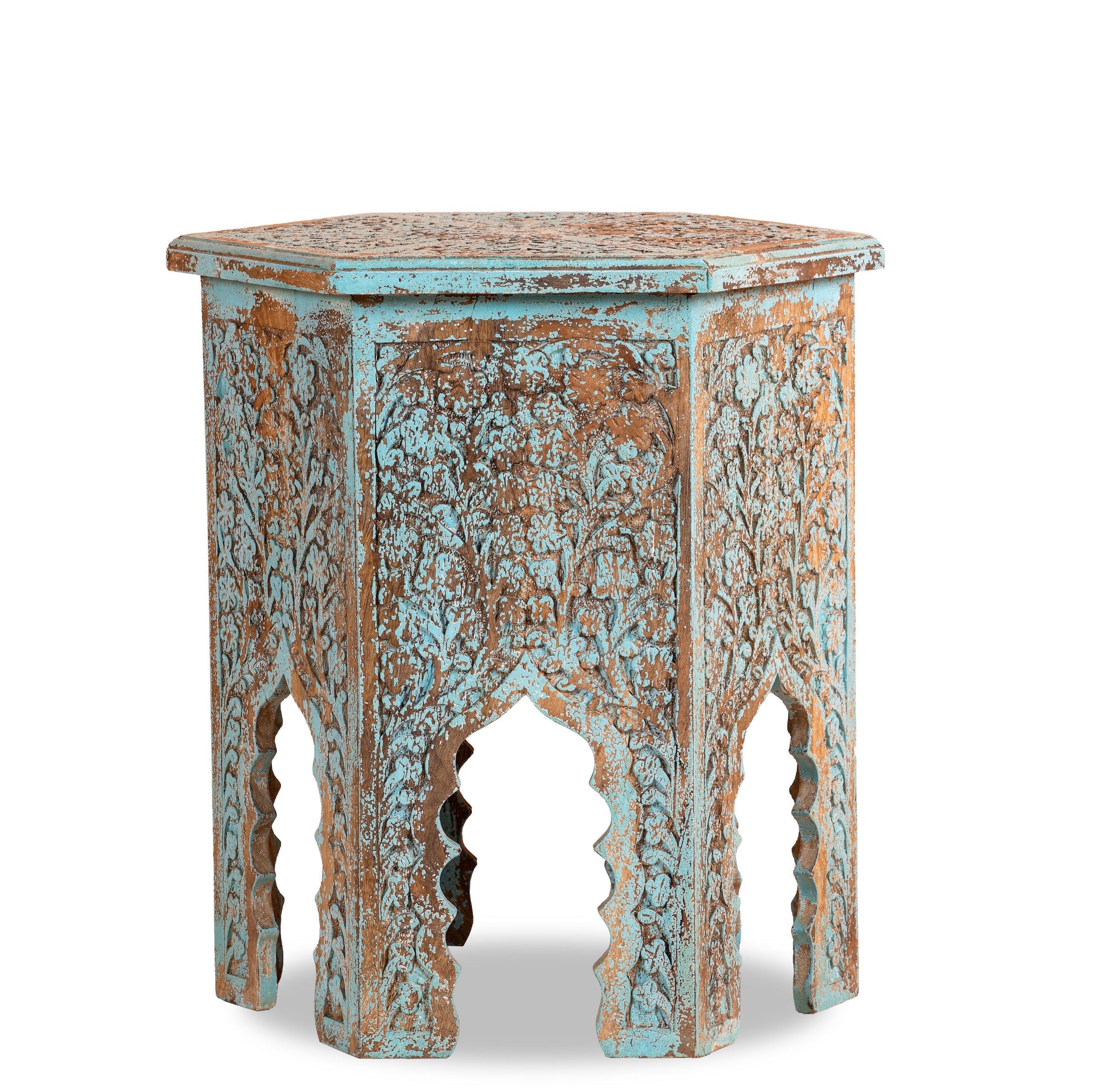 White background image of a hand carved decorative side table with arched design next to a bed in a bedroom.