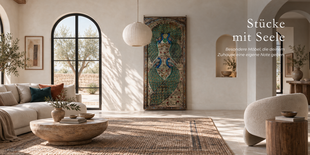 A large vertical framed wall art piece featuring a detailed peacock design in teal, green, gold, and brown tones, displayed in a bright, modern living room with a beige sofa, wooden coffee table, and arched window.