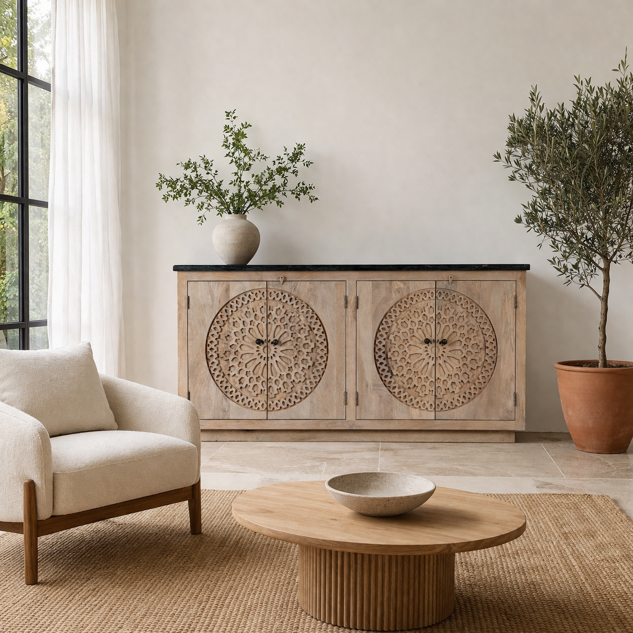 Lifestyle image of a wooden sideboard with decorative carvings and a black marble top in a living room setting with a mirror, flowers, and a couch.