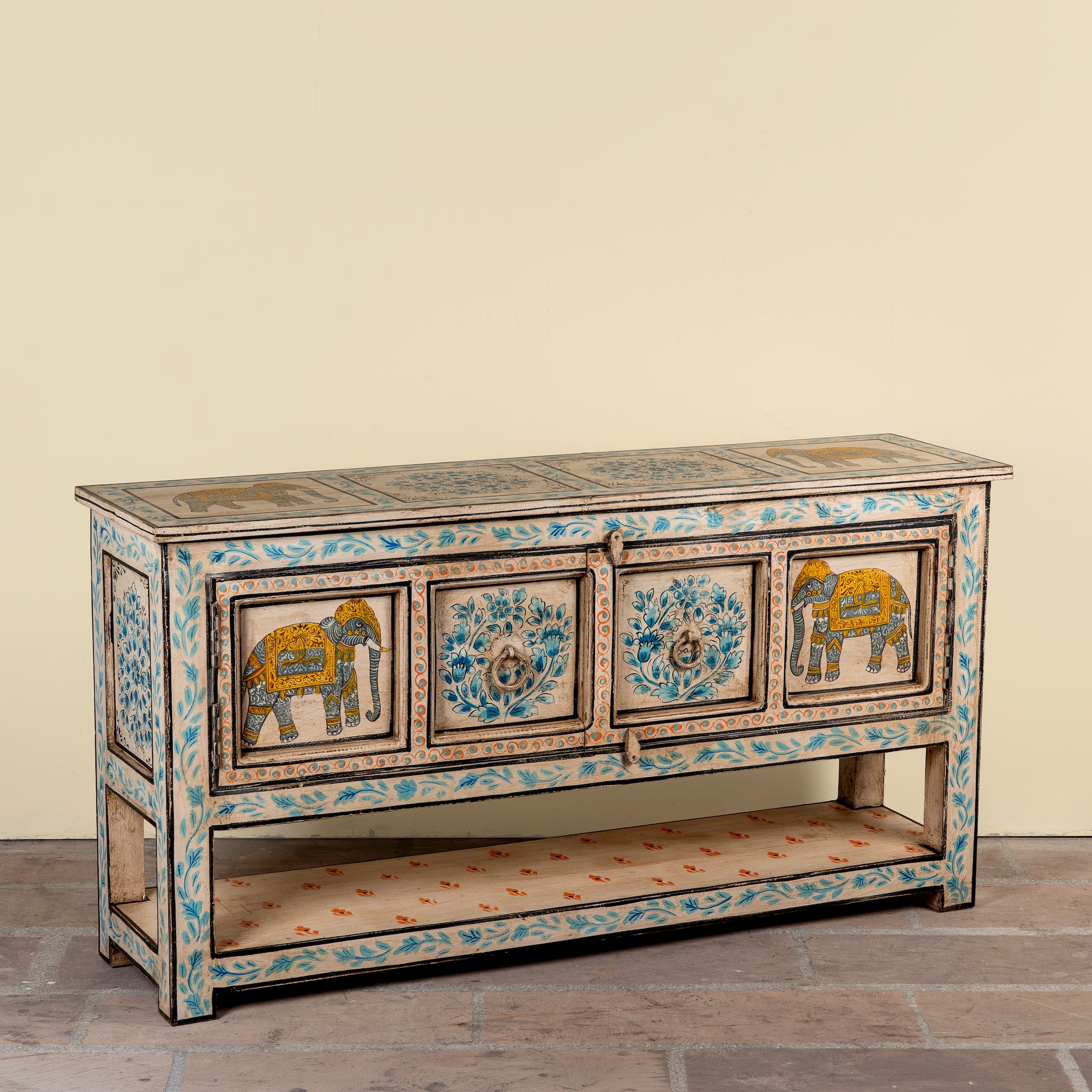 Side angle image of a Aakash hand painted reclaimed wood console table with blue floral and elephant motifs, storage and open shelf 114cm