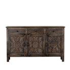 White background image of a dark brown mango wood sideboard with hand carved floral design, 3 drawers and 3 doors.