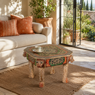 Lifestyle image of a Aaroh hand-painted reclaimed wood coffee table with sculpted tiger heads and colourful ornamental design 80cm