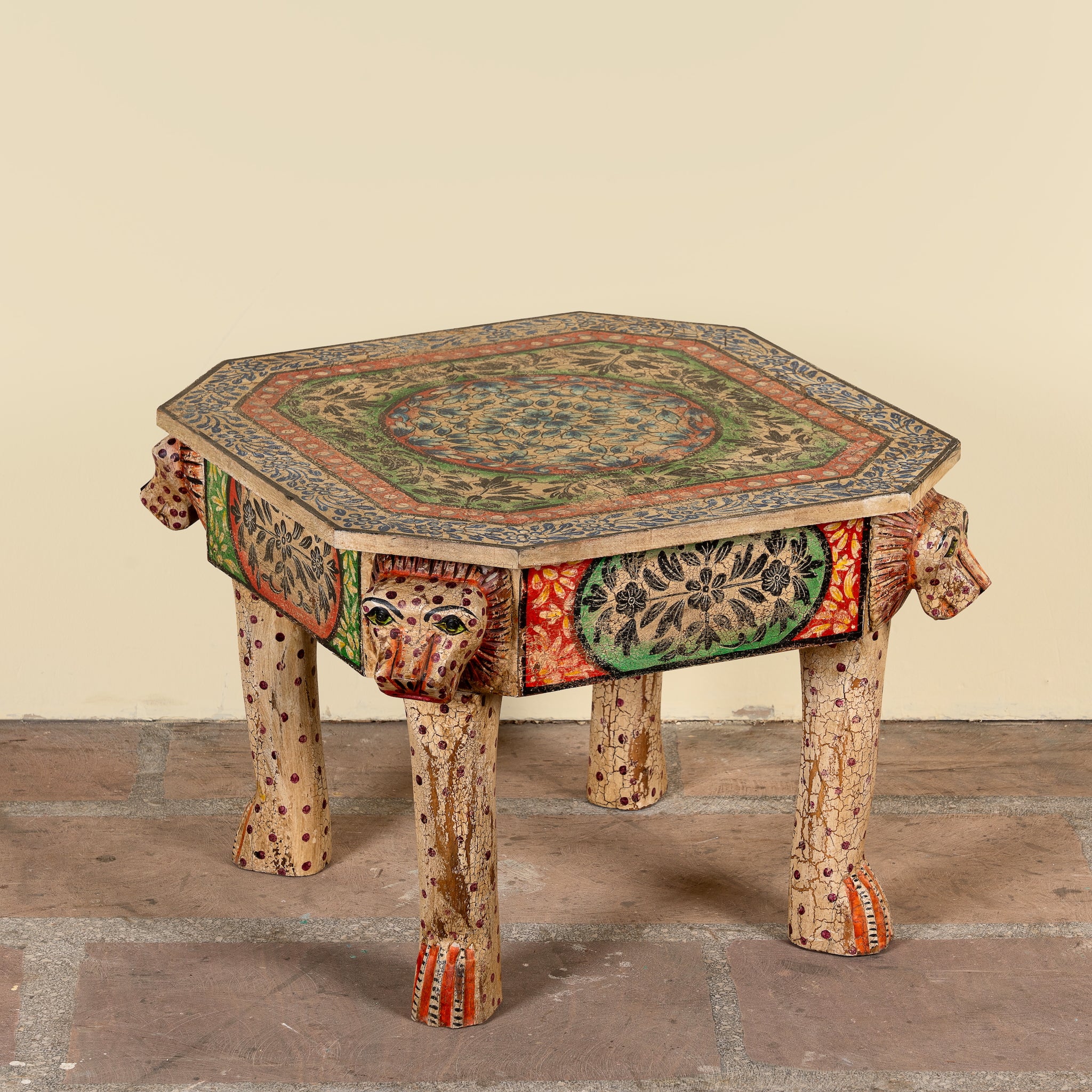 Side angle image of a Aaroh hand-painted reclaimed wood coffee table with sculpted tiger heads and colourful ornamental design 80cm
