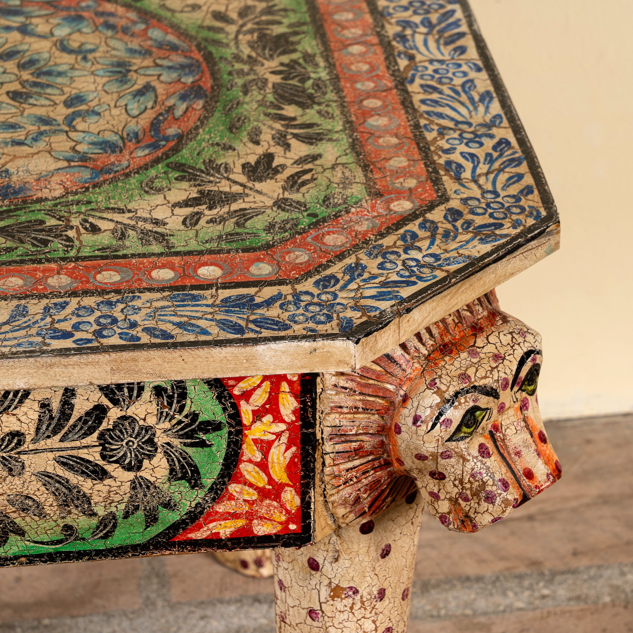Close up image of a Aaroh hand-painted reclaimed wood coffee table with sculpted tiger heads and colourful ornamental design 80cm