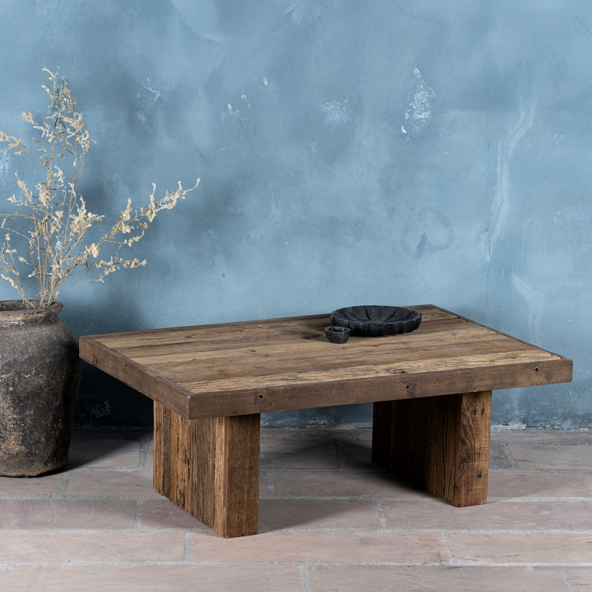 Front view of a rectangular rustic coffee table constructed from reclaimed wood, featuring a thick plank-style top and wide block legs, all with a naturally weathered finish that highlights the wood’s grain and imperfections.
