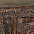 Close up image of a of a dark brown hand carved mango wood sideboard with floral design and ample storage.