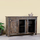 Side angle image with open doors of a dark brown hand carved mango wood sideboard with floral design and ample storage.