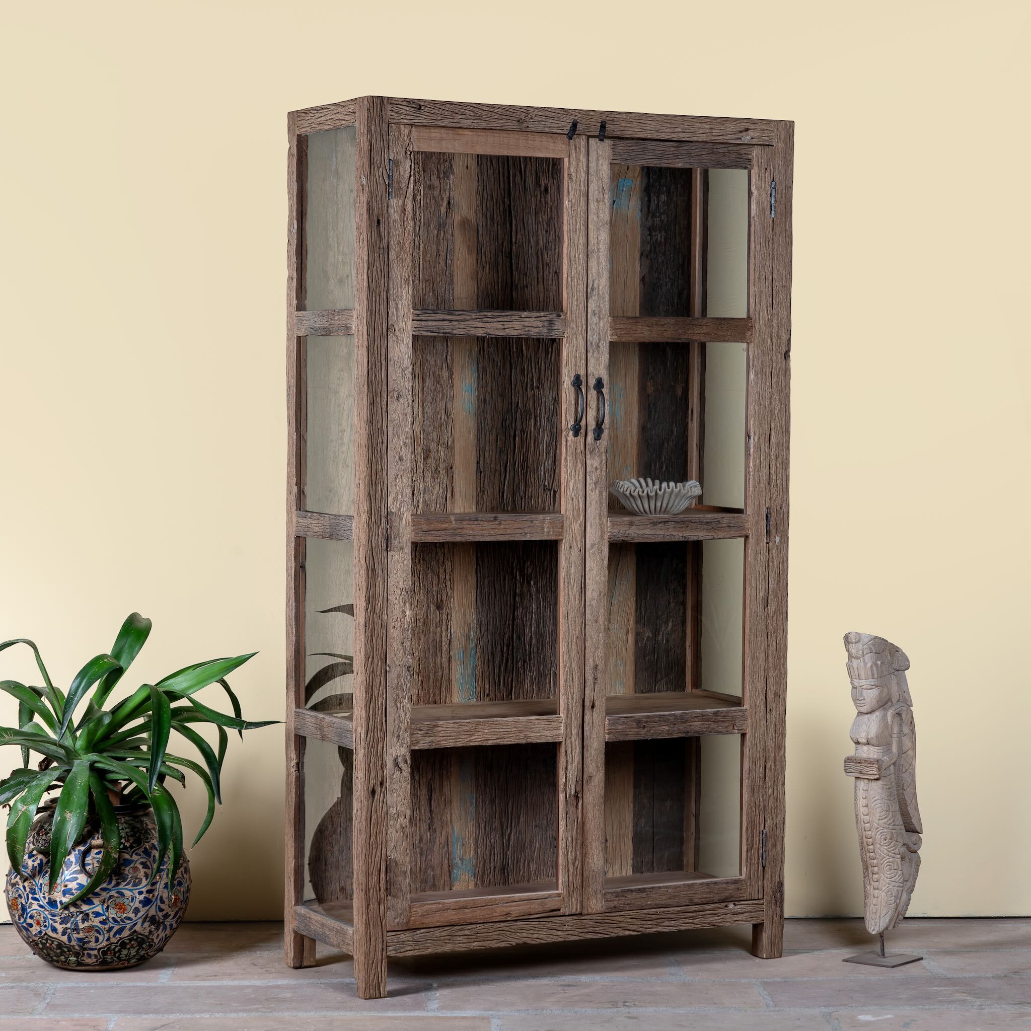 Side angle image of a driftwood display cabinet with 2 glass doors and 4 shelfs in rustic design.