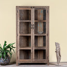 Lifestyle image of a driftwood display cabinet with 2 glass doors and 4 shelfs in rustic design.