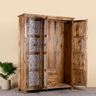 Side angle image with open doors of a hand carved wardrobe with floral design made of mango wood in vintage style.