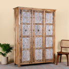 Side angle image of a hand carved wardrobe with floral design made of mango wood in vintage style.