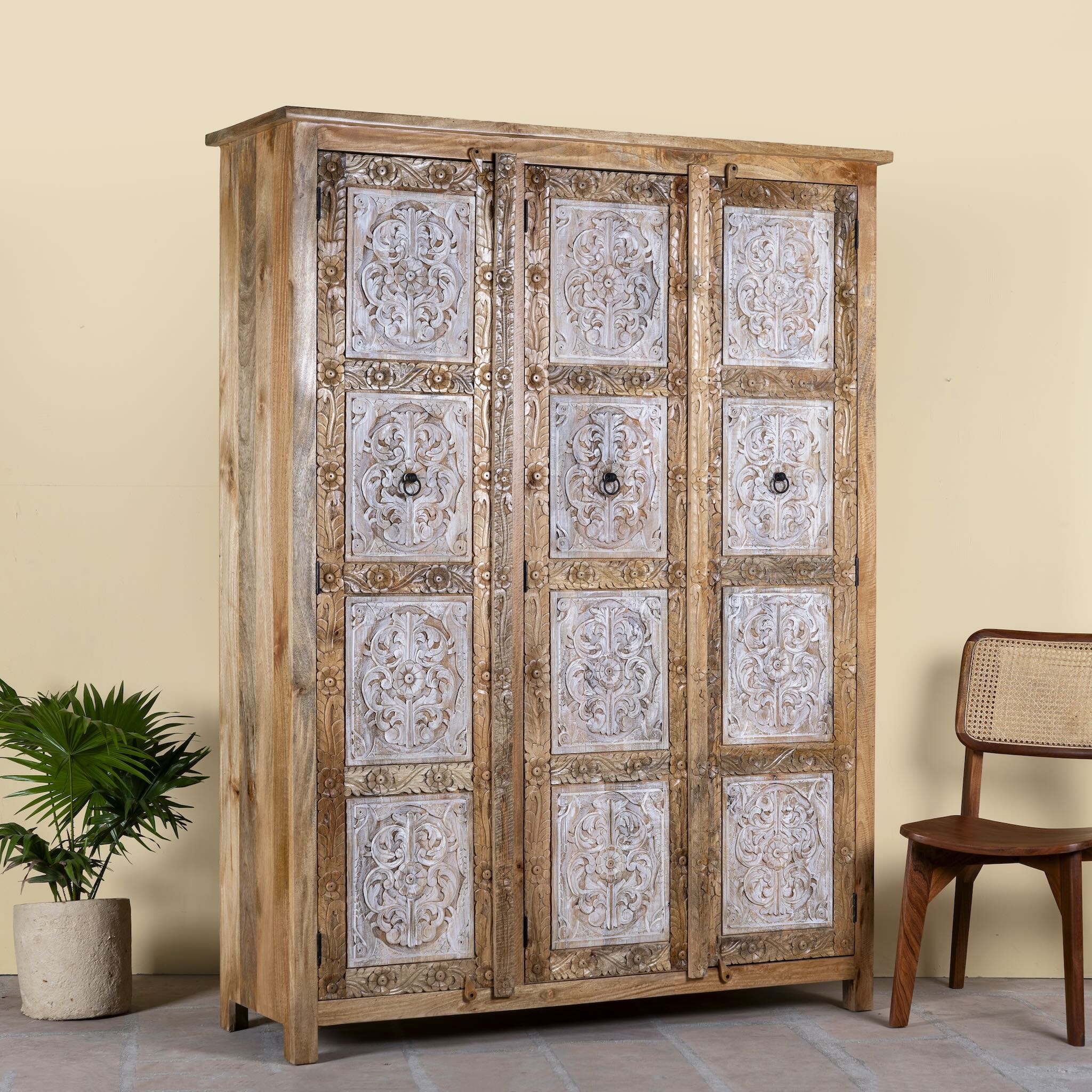 Side angle image of a hand carved wardrobe with floral design made of mango wood in vintage style.