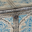 Close up image of a decorative wooden box coffee table with intricate hand painted patterns made of reclaimed wood in a living room setting