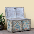 Side angle image with open lid of a decorative wooden box coffee table with intricate hand painted patterns made of reclaimed wood in a living room setting