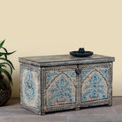 Side angle image of a decorative wooden box coffee table with intricate hand painted patterns made of reclaimed wood in a living room setting