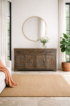 Lifestyle imagination of a Hand-carved mango wood sideboard Aavya in a vintage dark finish, featuring four drawers and four carved cabinet doors with Indian-inspired motifs. A bold piece of vintage furniture and unique Indian craftsmanship.