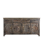 White background image of a hand-carved mango wood sideboard Aavya in a vintage dark finish, featuring four drawers and four carved cabinet doors with Indian-inspired motifs. A bold piece of vintage furniture and unique Indian craftsmanship.