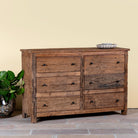 Side angle image of a chest of 6 drawers in Japandi style made of reclaimed dark wood.