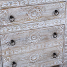 Close up image of a hand carved white washed mango wood chest of 6 drawers in mediterranean design with iron 
handles.
