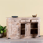 Side angle image with open doors of a Abhiraj hand carved mango wood sideboard with distressed cream finish, three drawers and three doors, 150cm