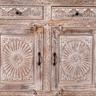 Close up image of a Abhiraj hand carved mango wood sideboard with distressed cream finish, three drawers and three doors, 150cm