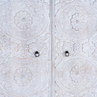 Close up image of a hand carved white washed mango wood wardrobe in vintage design.