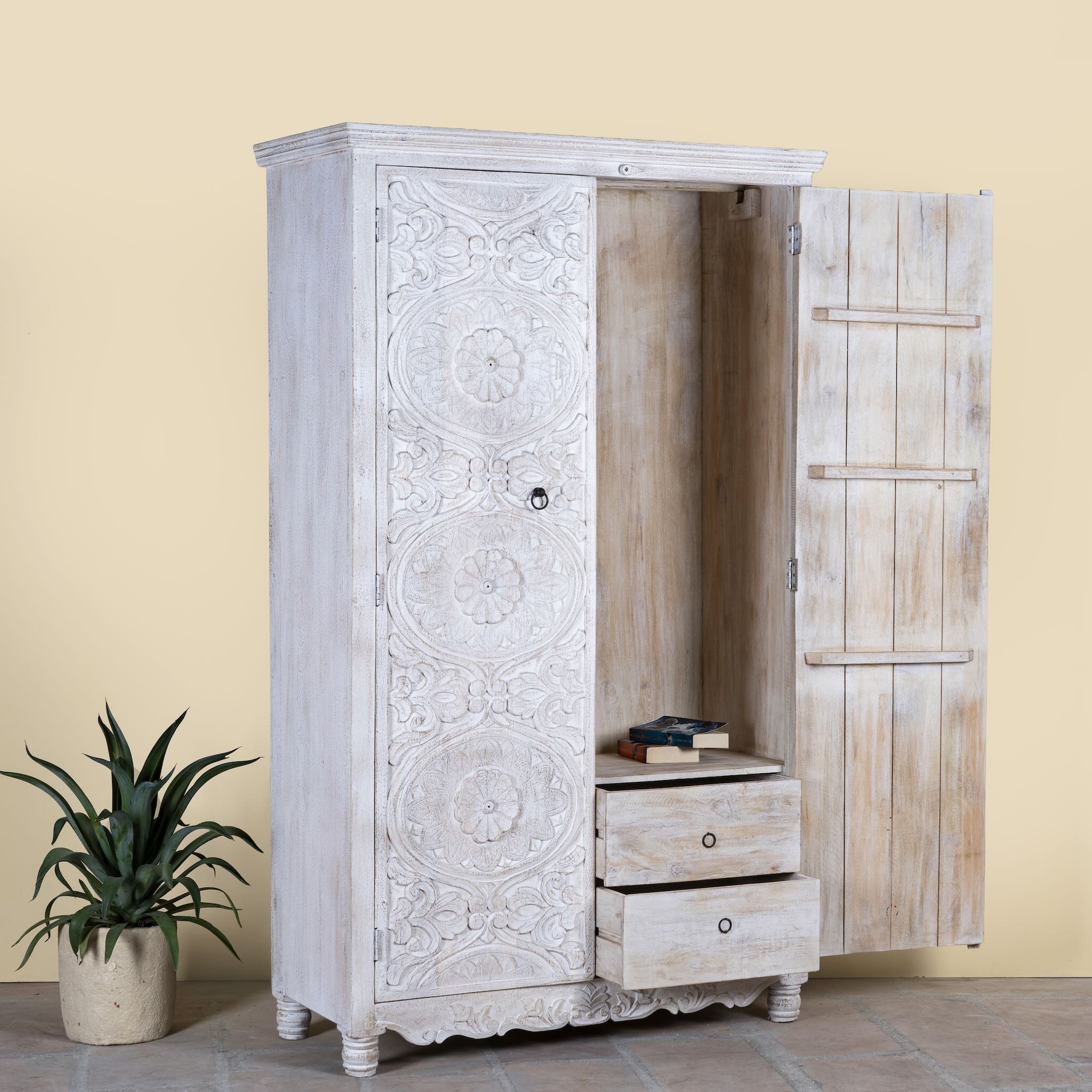 Side angle image with open door of a hand carved white washed mango wood wardrobe in vintage design.
