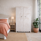 Lifestyle image of a hand carved white washed mango wood wardrobe in vintage design.