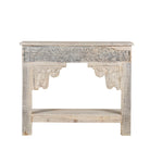 White background image of a handcrafted reclaimed teak wood console table with sandblasted finish, carved floral detailing, vintage corbels, and lower shelf; perfect for styling with vintage home accessories, 133 × 62 × 90 cm.