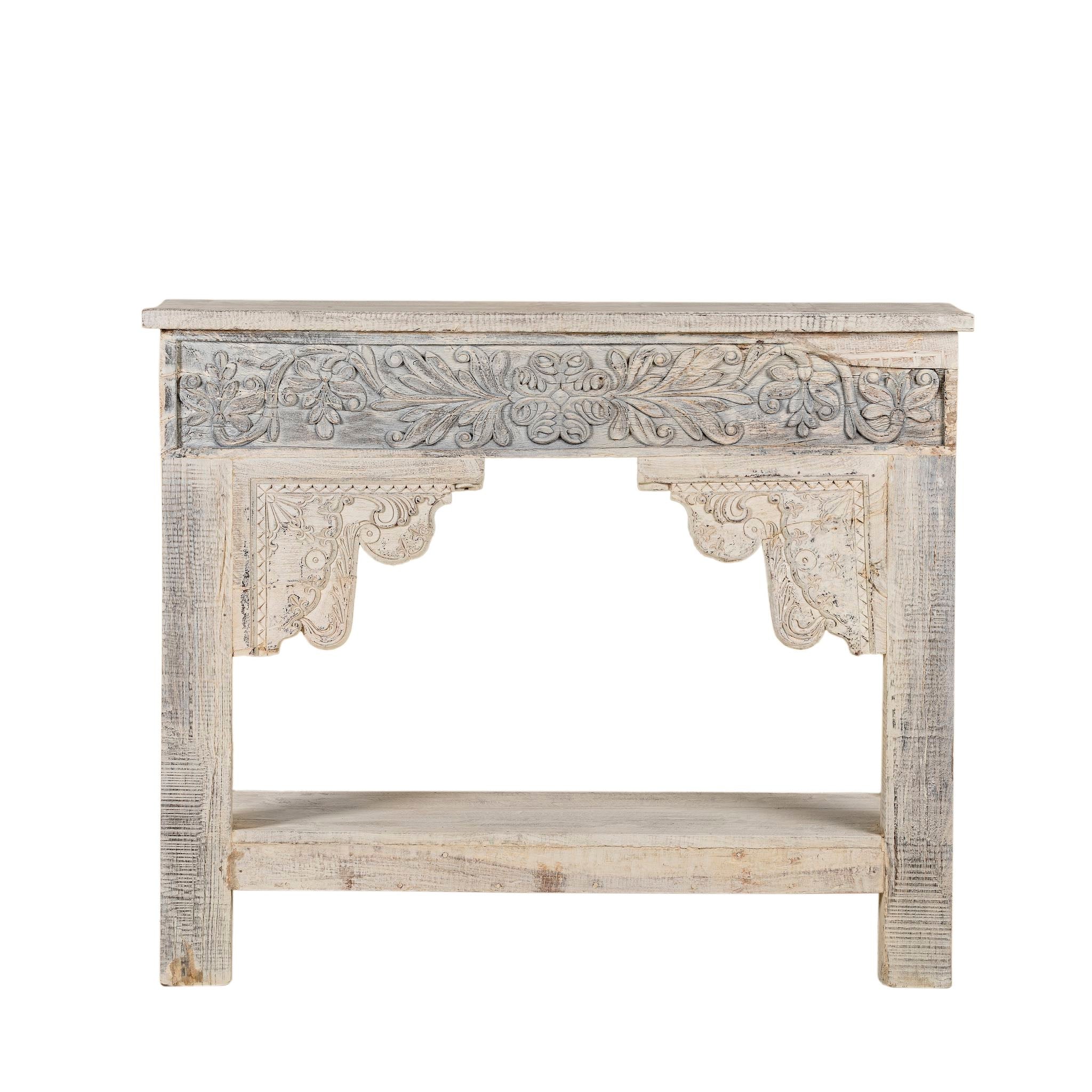 White background image of a handcrafted reclaimed teak wood console table with sandblasted finish, carved floral detailing, vintage corbels, and lower shelf; perfect for styling with vintage home accessories, 133 × 62 × 90 cm.