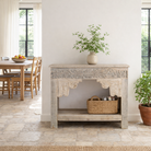 Lifestyle imagination of a handcrafted reclaimed teak wood console table with sandblasted finish, carved floral detailing, vintage corbels, and lower shelf; perfect for styling with vintage home accessories, 133 × 62 × 90 cm.