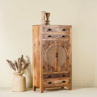 Side angle image of a handcrafted mango wood cabinet Agnayi with rattan inserts and floral carvings, rattan furniture for bohemian interior, 80 × 40 × 148 cm.