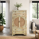 Lifestyle image of a green-washed mango wood cabinet with floral carvings, rattan door inserts, versatile living room furniture, 80 × 148 × 40 cm.
