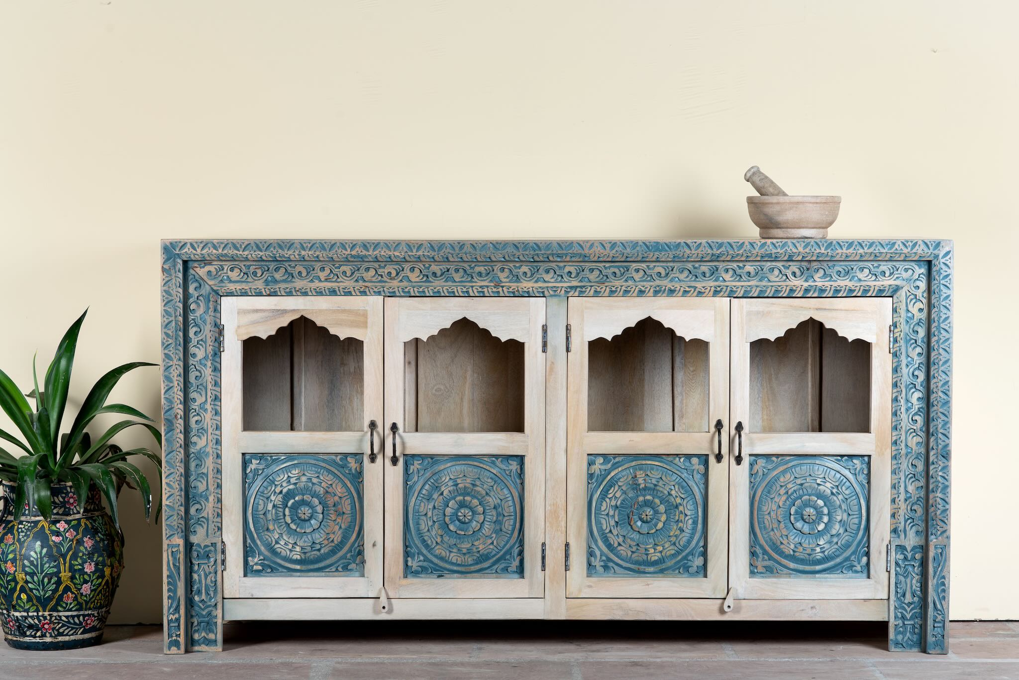 Image of a hand carved showcase made of natural mango wood in white washed with blue floral accents and half glass doors in vintage design.