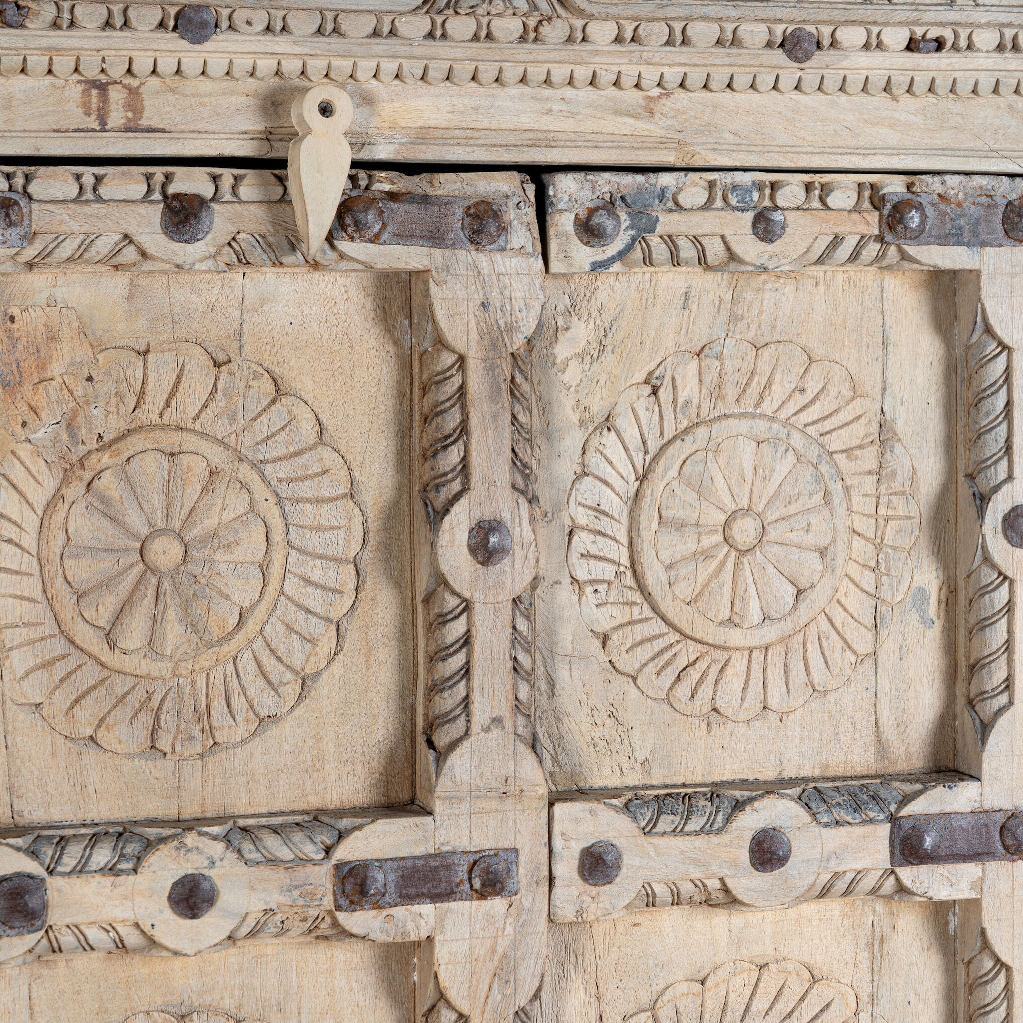 Close up image of a reclaimed teak wood cabinet Ahara with Mediterranean design, featuring hand-carved antique Indian doors and metal accents. A unique piece of old door furniture ideal for stylish, character-rich living room storage.