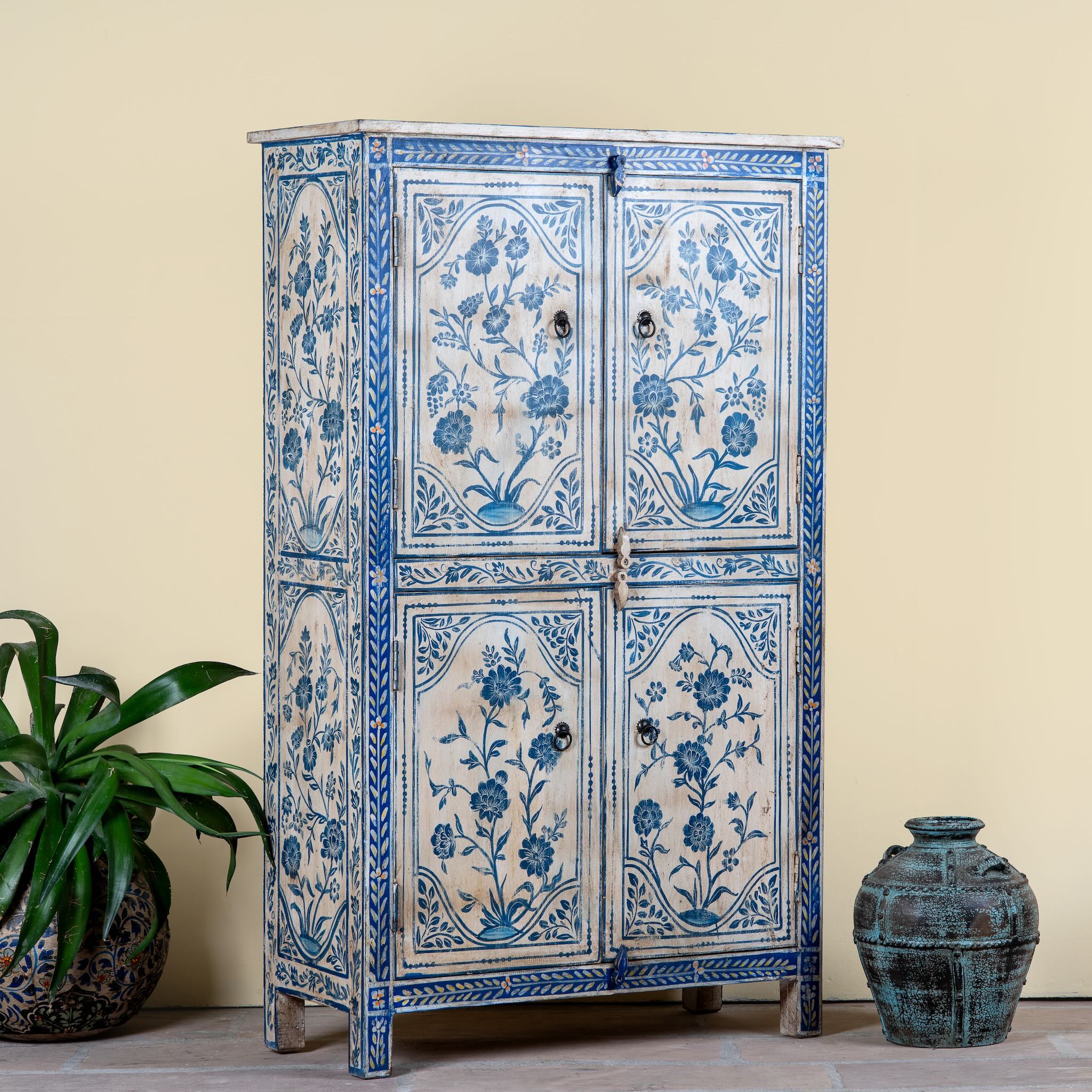 Side angle image of a unique hand painted wardrobe made of reclaimed wood with floral design, 4 doors and ample storage.