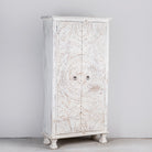 Side angle image of an Aila handcrafted solid mango wood wardrobe with intricately hand-carved Indian doors, four spacious storage compartments, natural wood grain, and Mediterranean-inspired design, 180cm.