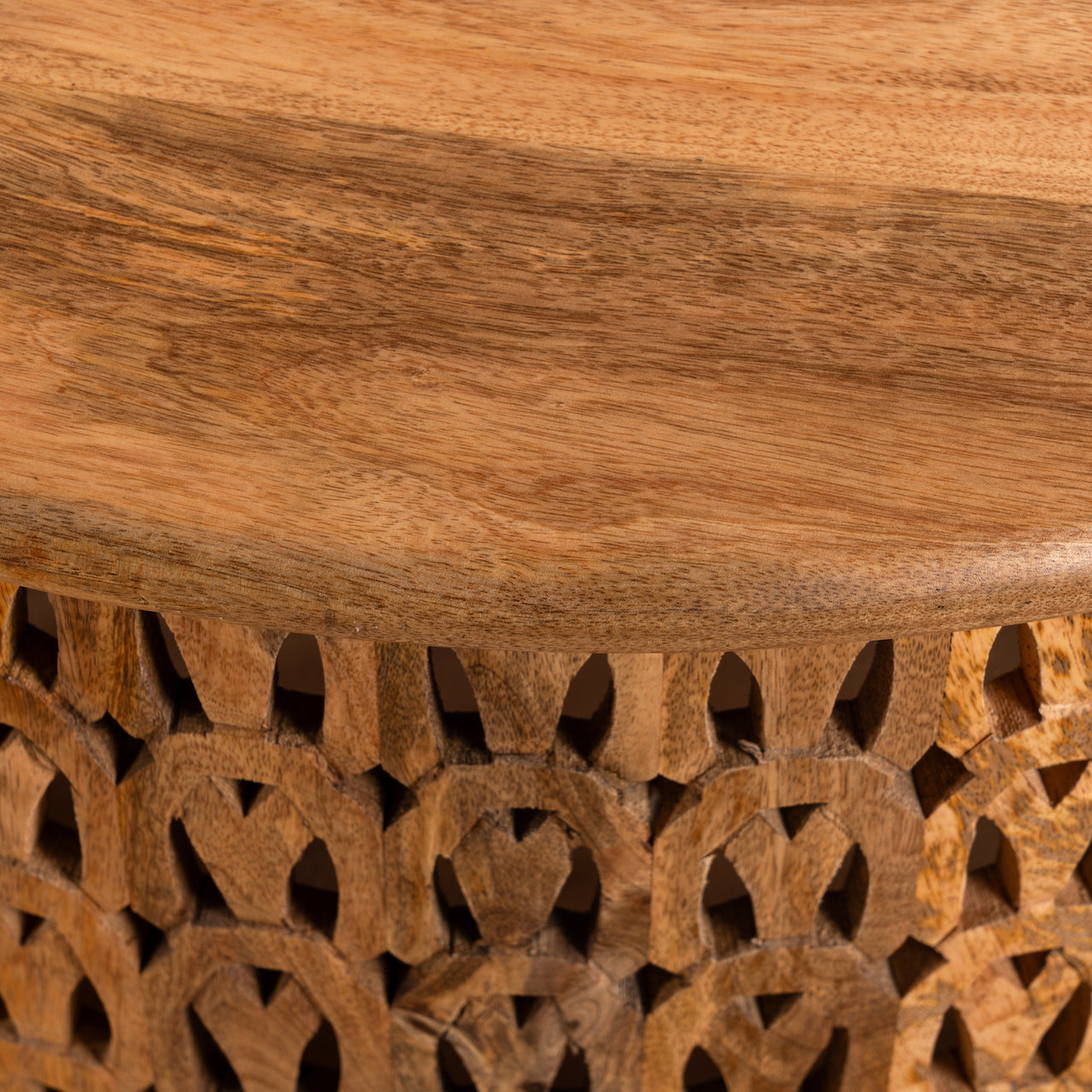Close up image of a round mango wood coffee table with hand-carved lattice base and smooth natural top; carved coffee table mango wood, 90 cm diameter, 45 cm height.