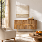 Lifestyle image of a handcrafted mango wood sideboard with curved door panels and brass-plated legs—minimalistic style living room furniture with natural elegance.