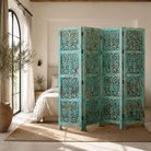 Lifestyle image of a hand-carved green mango wood folding room divider with delicate carved patterns, natural variations, and warm boho style for unique interiors.
