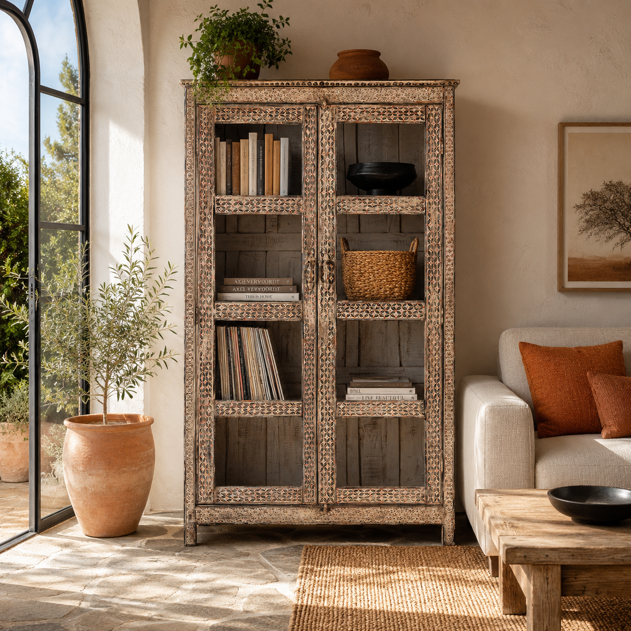 Lifestyle image of a handcrafted reclaimed teak wood display cabinet with glass doors and hand-painted Sanskrit symbols – sustainable furniture with vintage soul and artisanal charm.