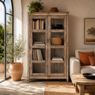 Lifestyle image of a handcrafted reclaimed teak wood display cabinet with glass doors and hand-painted Sanskrit symbols – sustainable furniture with vintage soul and artisanal charm.